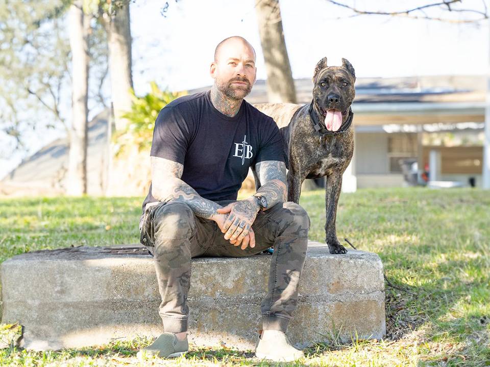 A certified Presa Canario therapy dog wearing a therapy dog vest, sitting attentively next to its handler in a healthcare setting.